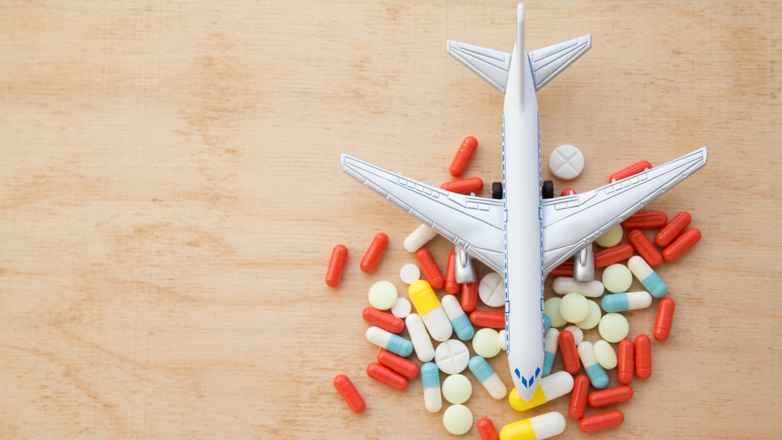 model airplane with multicolored pills from motion sickness close-up on a wooden background. flat lay. concept illness in travel